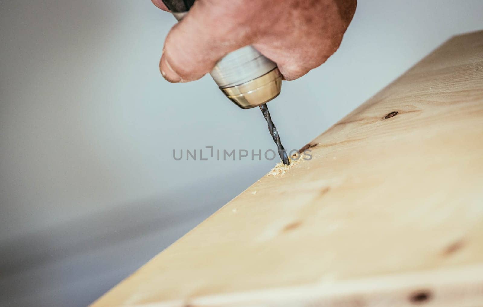 Craftsman is drilling in wood with drilling machine