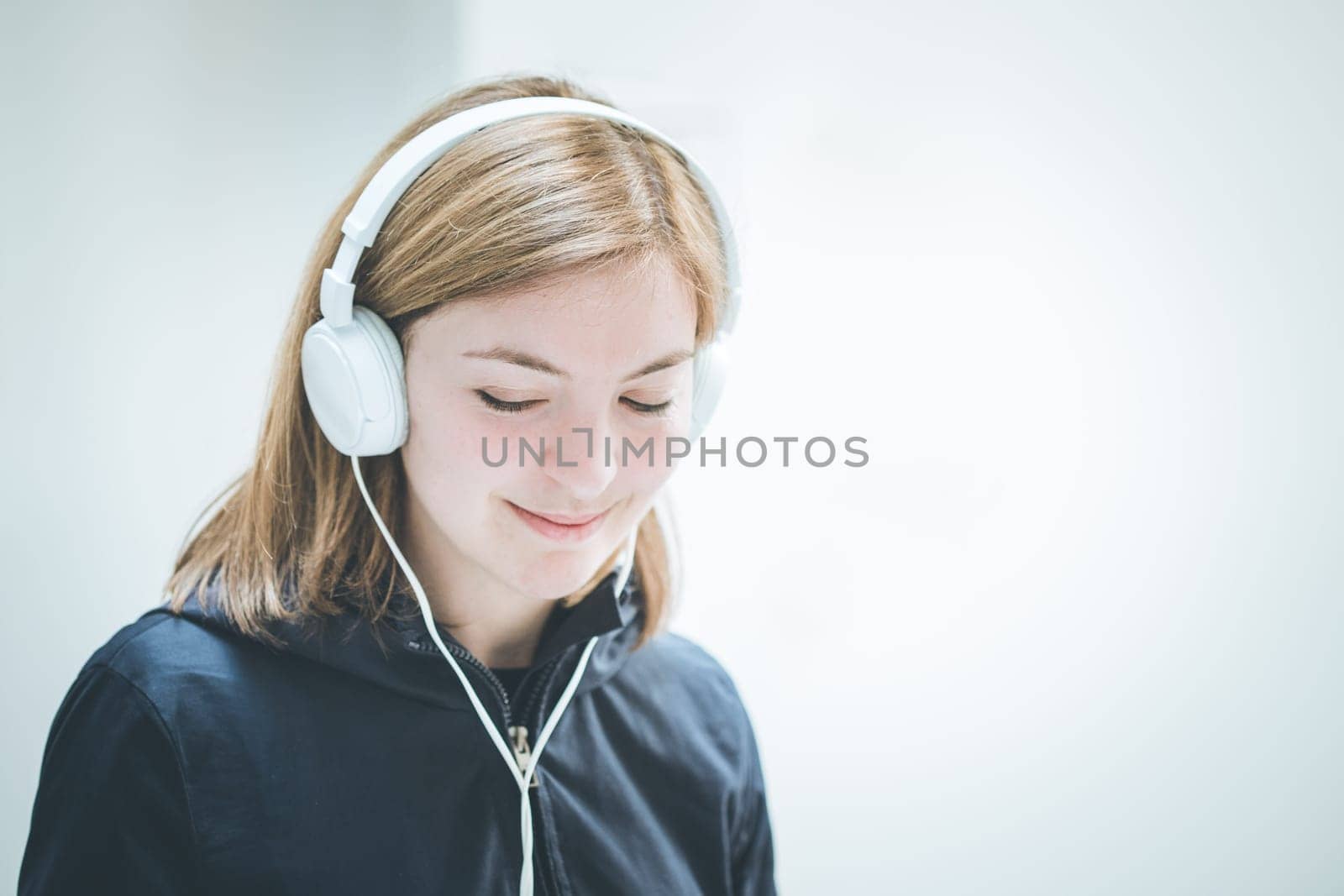 Young cute girl is listening to music with headphones