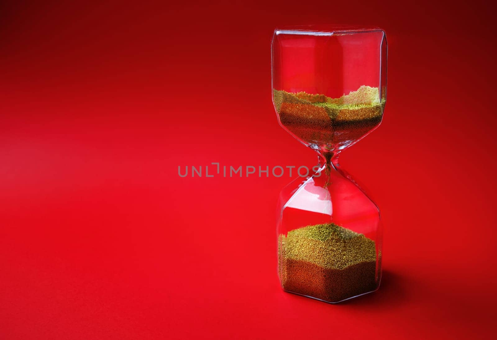 Hourglass on red background with copy space. Time concept.
