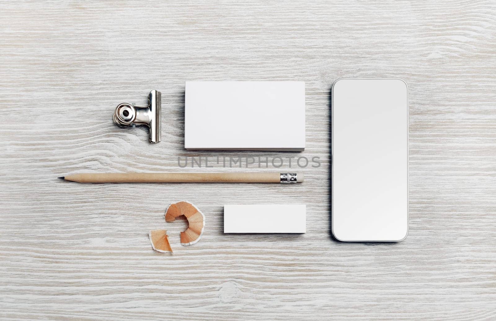 Branding mock up. Blank business card, smartphone, pencil and eraser on light wooden background. Flat lay.