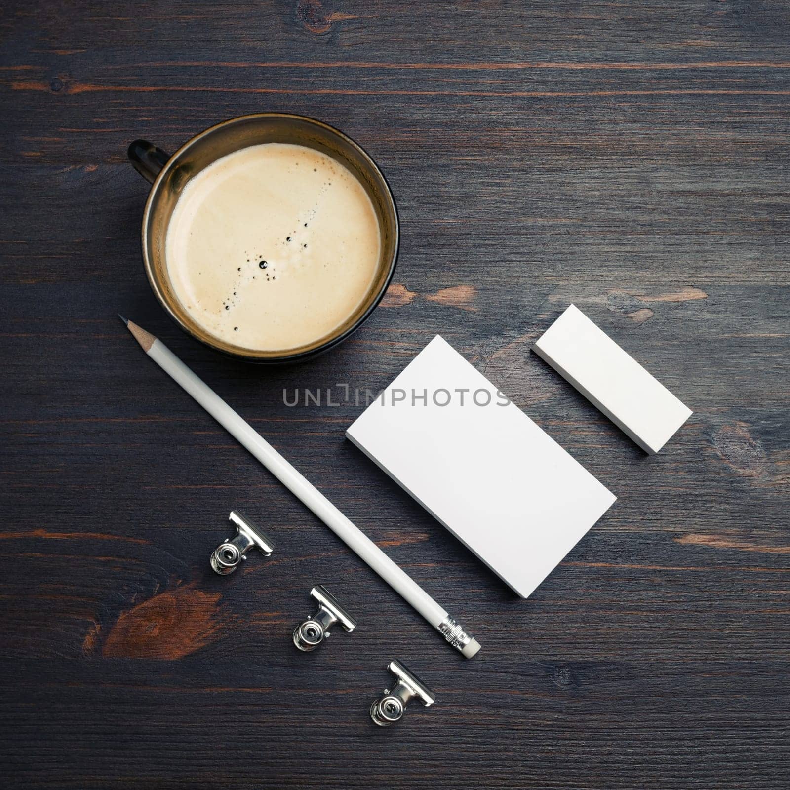 Coffee cup and blank stationery: business cards, pencil and eraser on wood table background. Top view. Flat lay.