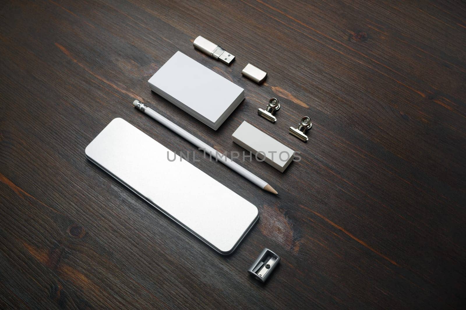 Photo of blank stationery set. Blank business card, pencil case, flash drive, pencil, eraser and sharpener on wooden background.