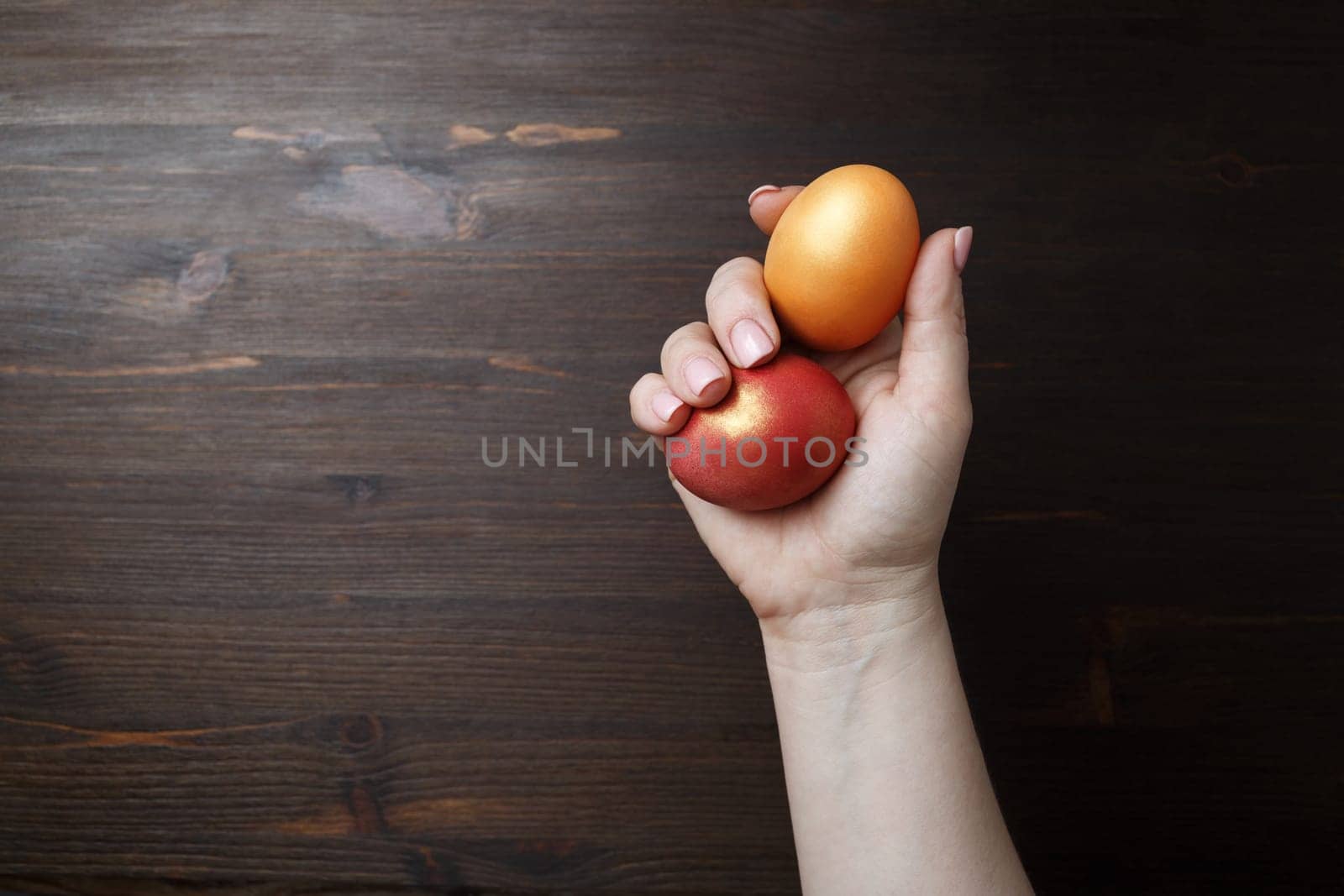 Easter eggs in female hand on wooden background.