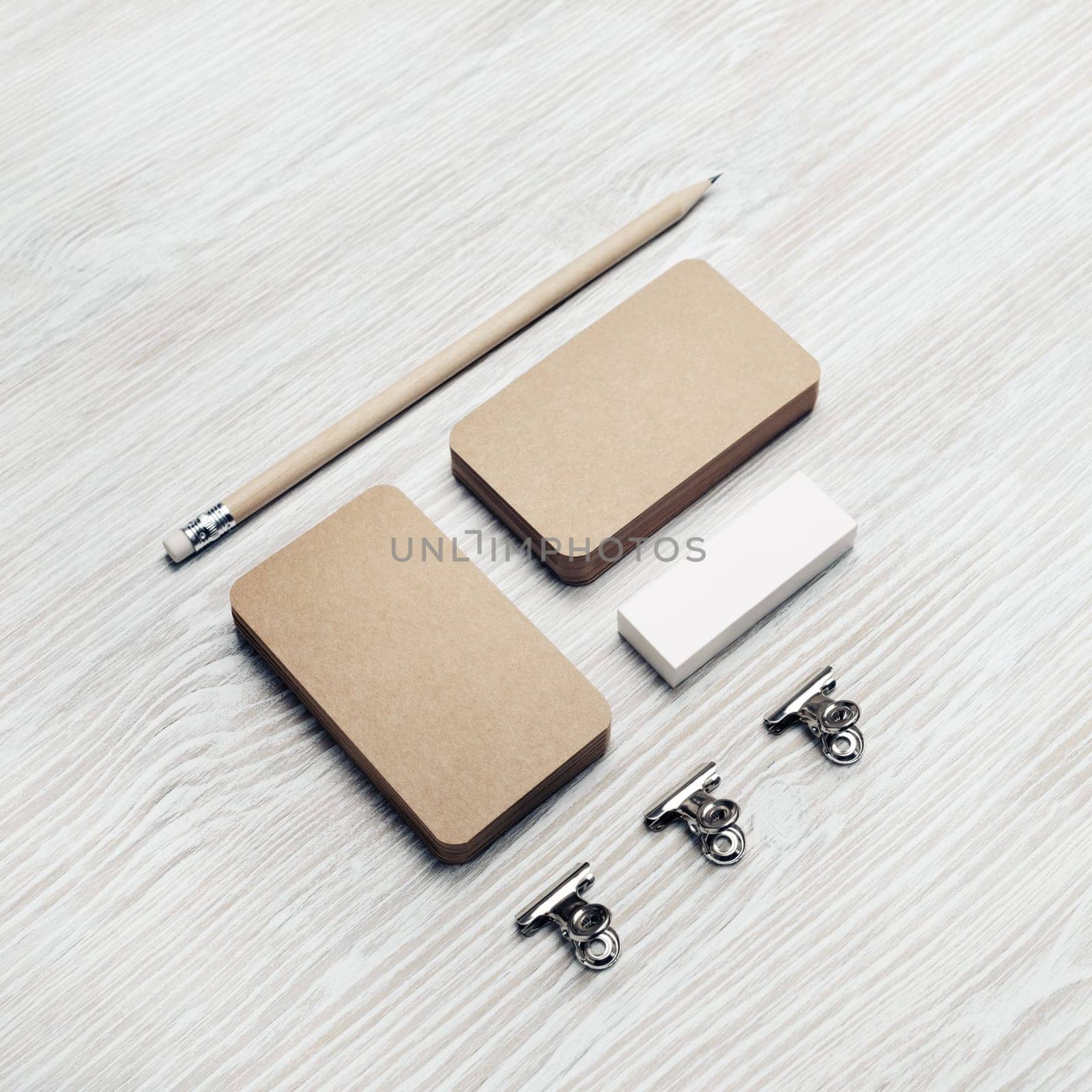 Blank stationery set. Kraft business cards, pencil and eraser on light wooden background. Branding identity. ID mockup.