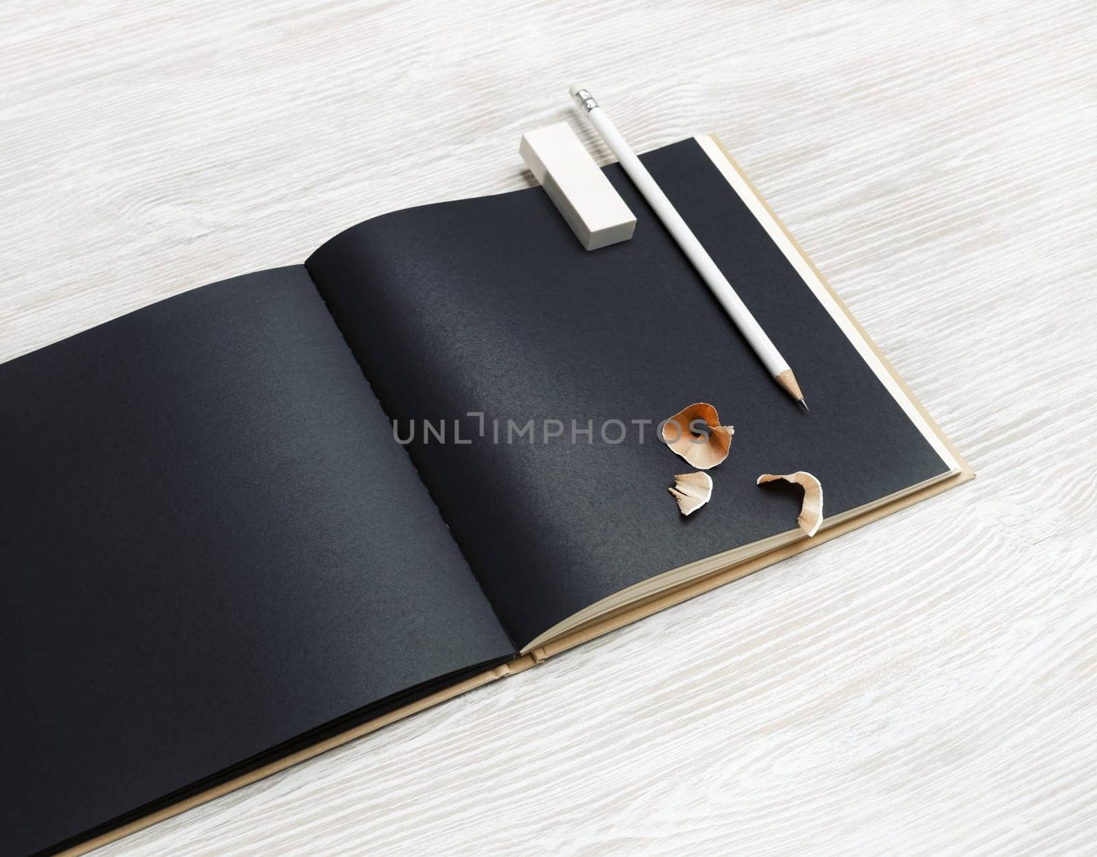 Black brochure, pencil and eraser on light wooden background.