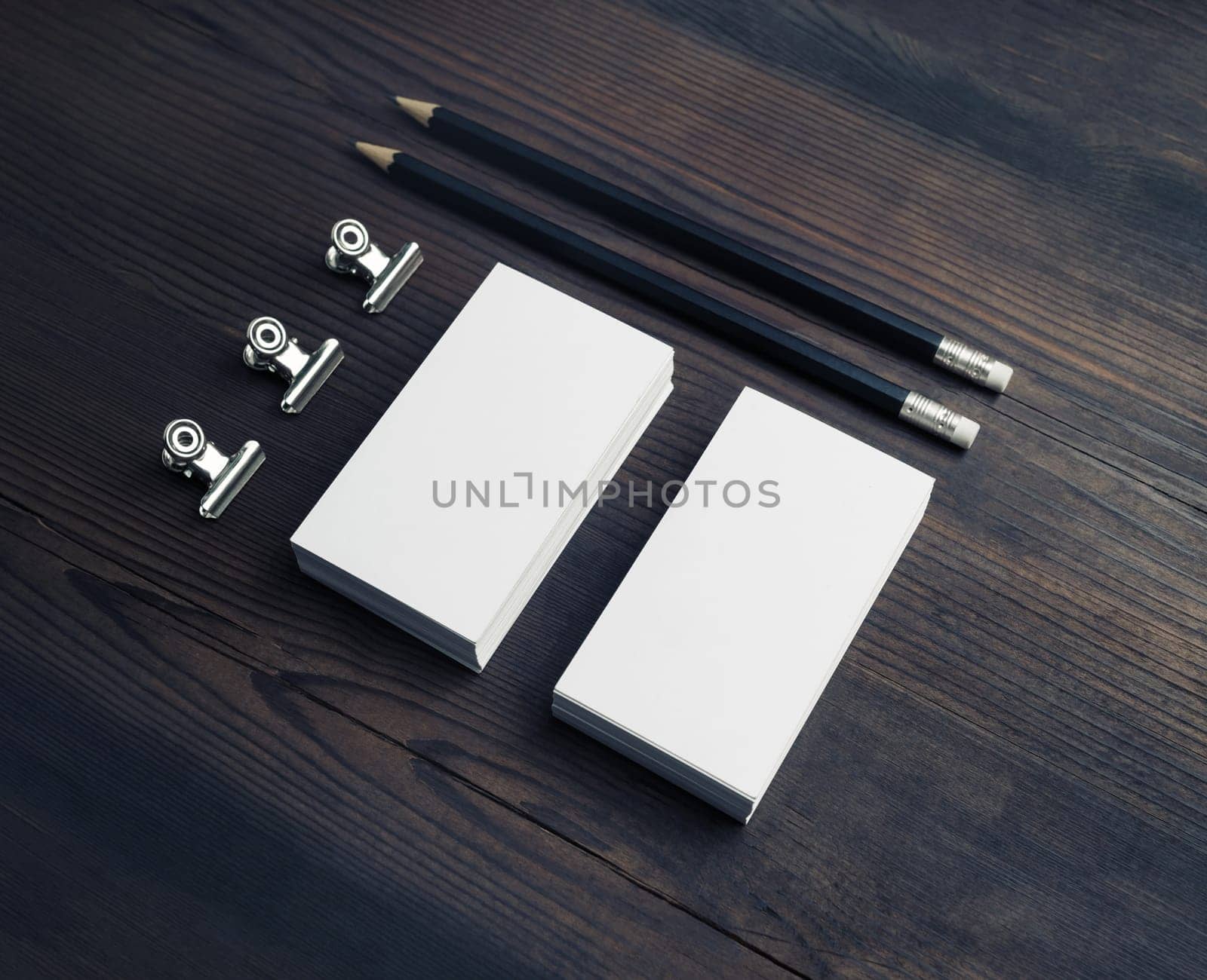 Blank business stationery on wooden background. Blank business cards, pencils and paper clips.