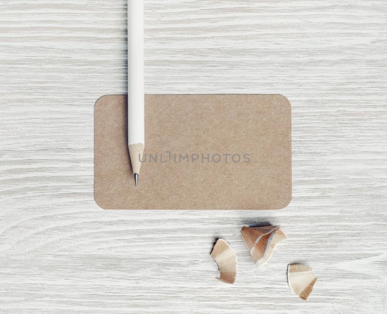 Photo of blank kraft business card and pencil on light wood table background. Blank stationery template. Top view. Flat lay.