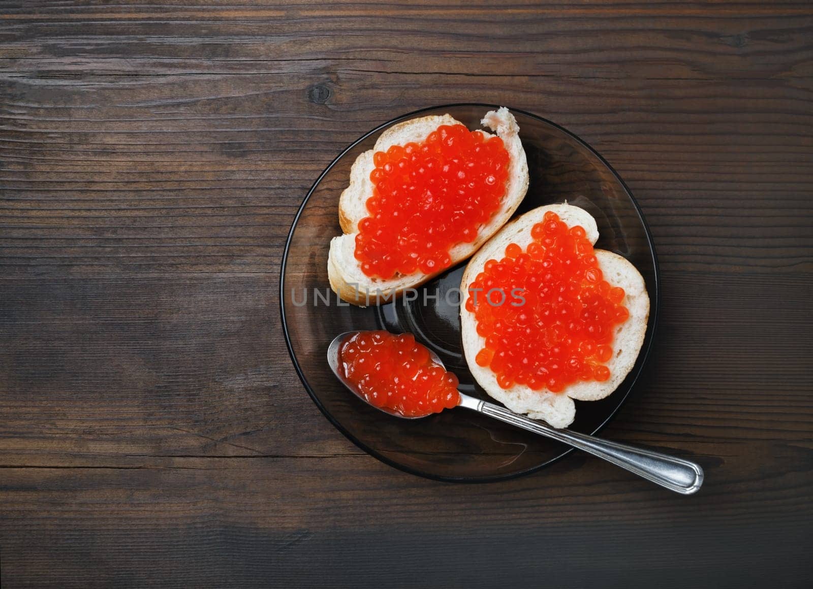 Delicious fresh red caviar, sandwiches, plate and spoon on wood table background. Top view. Flat lay.