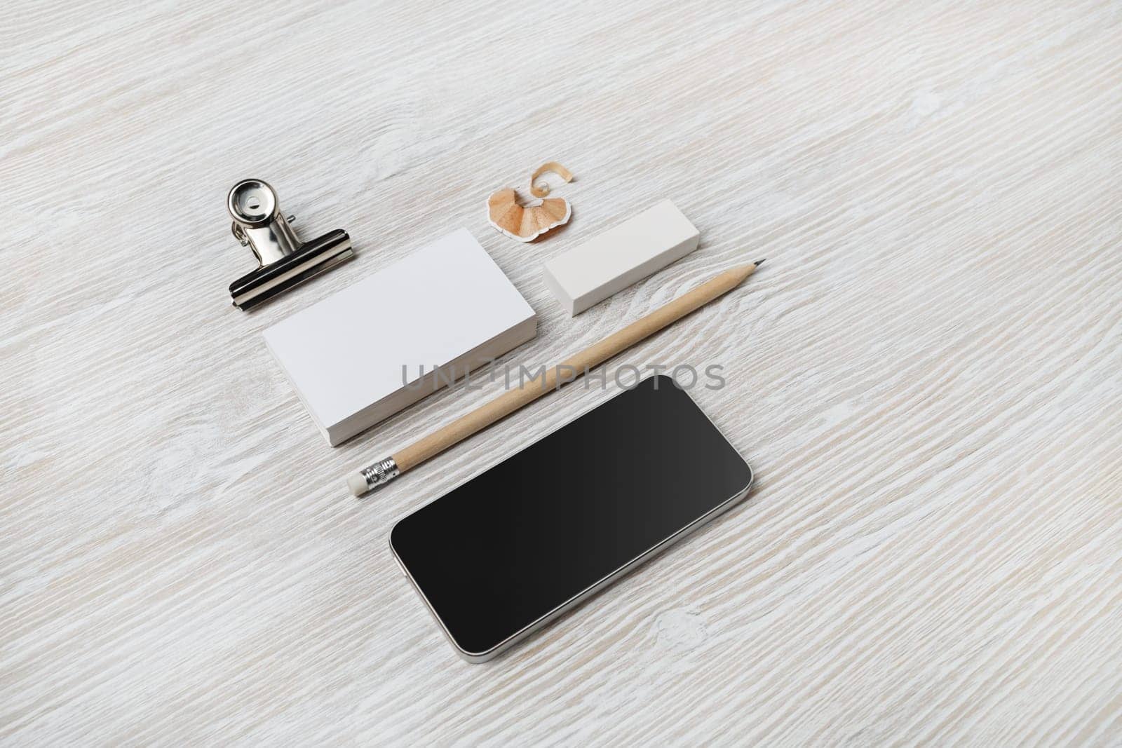 Blank branding mockup. Blank business cards, smartphone, pencil and eraser on light wood table background.