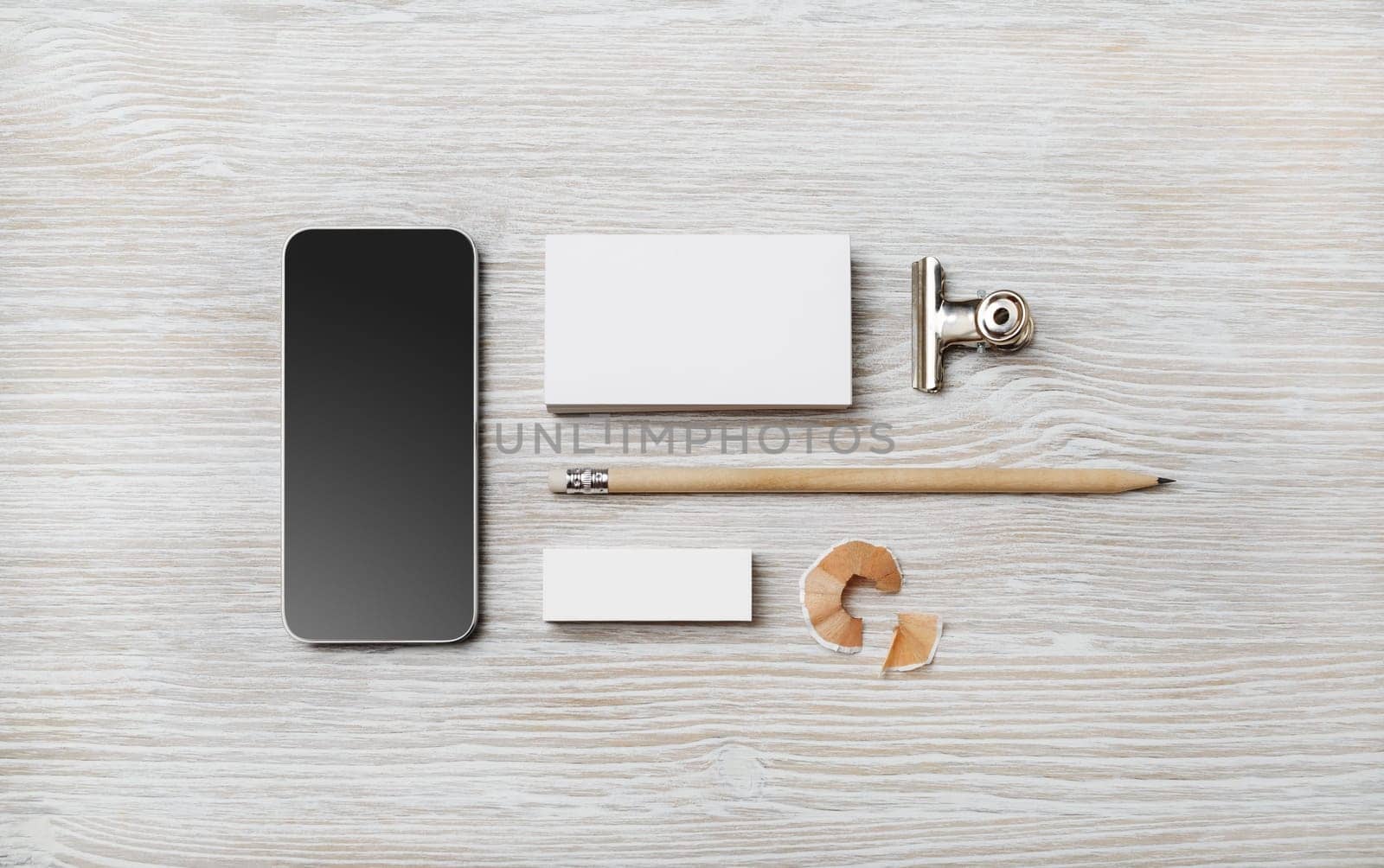 Blank business card, smartphone, pencil and eraser on light wood table background. Branding template. Top view. Flat lay.