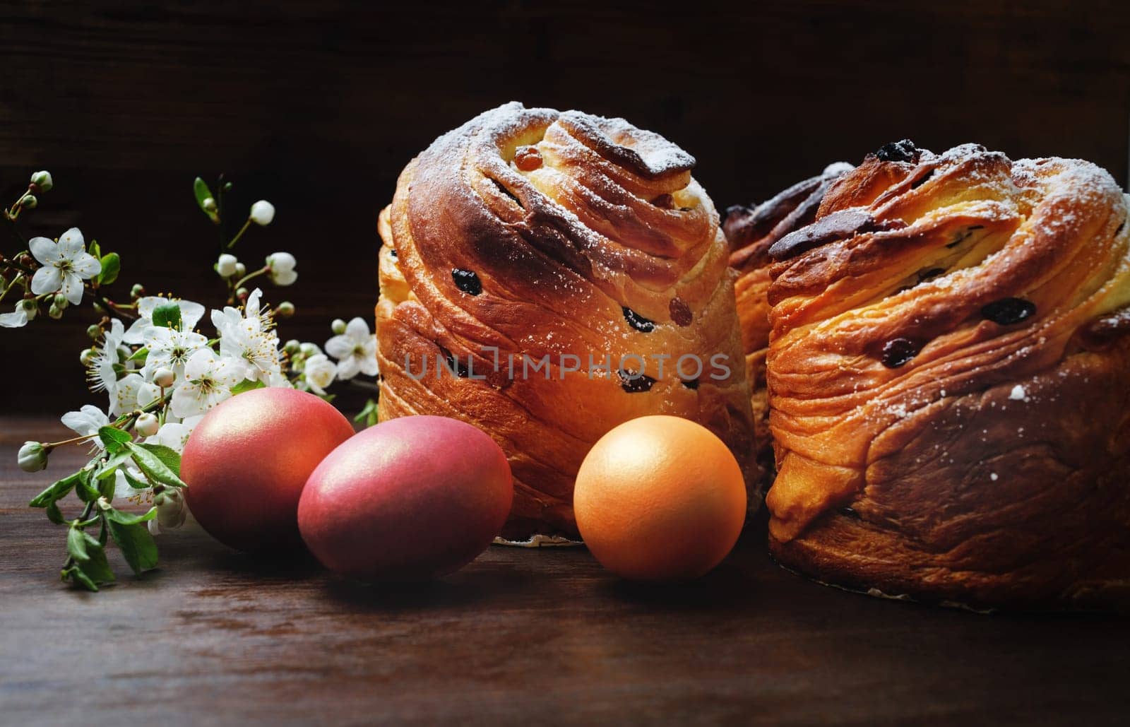 Easter eggs, sweet buns and spring flowers on wooden background.