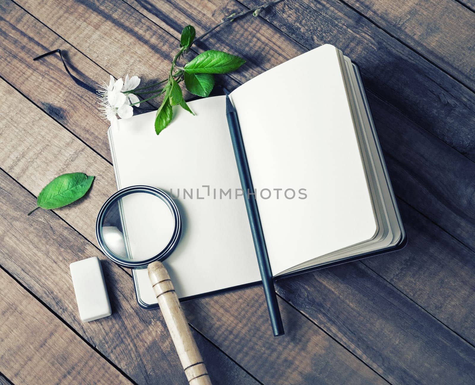 Blank notepad, magnifier, pencil and eraser on wooden background.