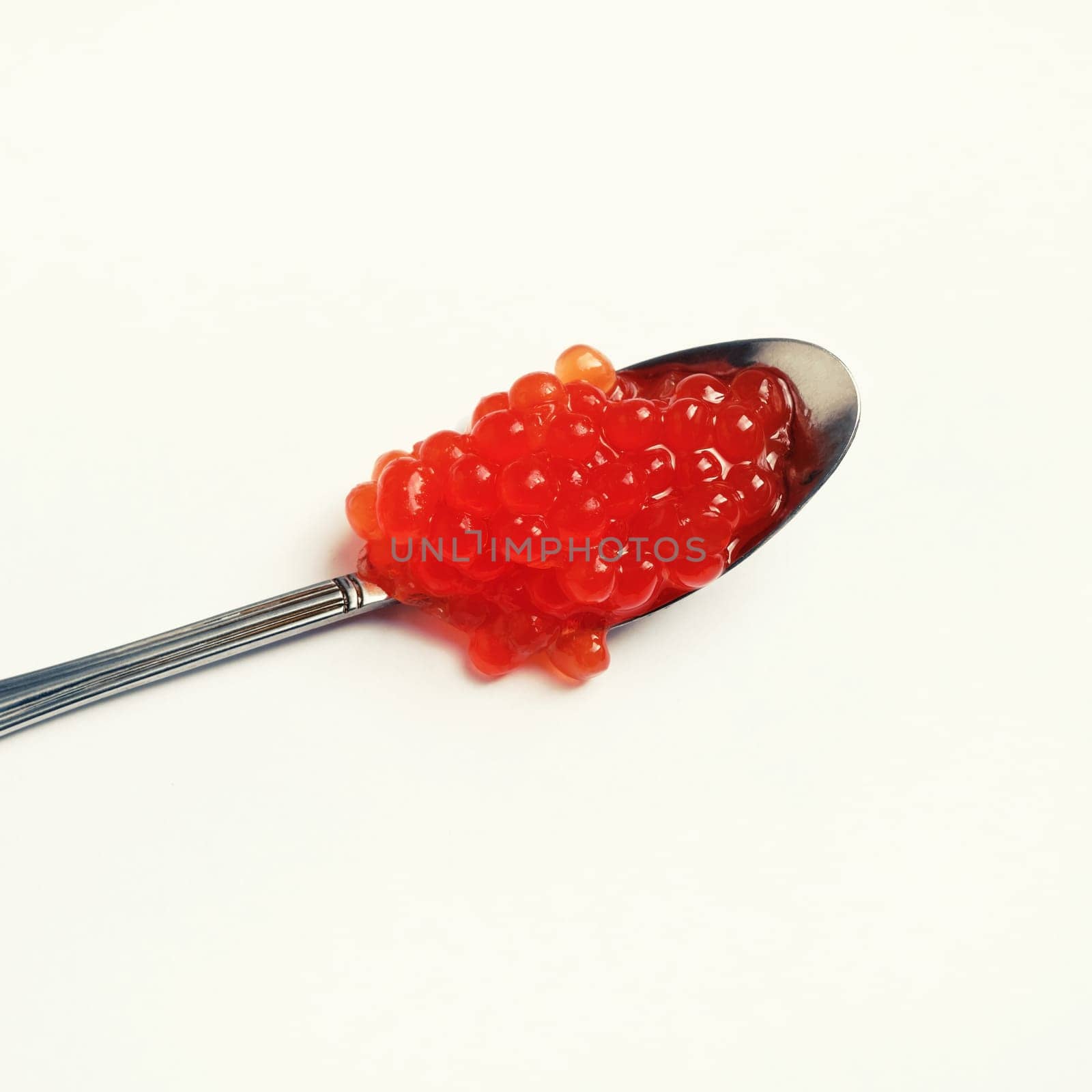 Spoon and red caviar on light background.