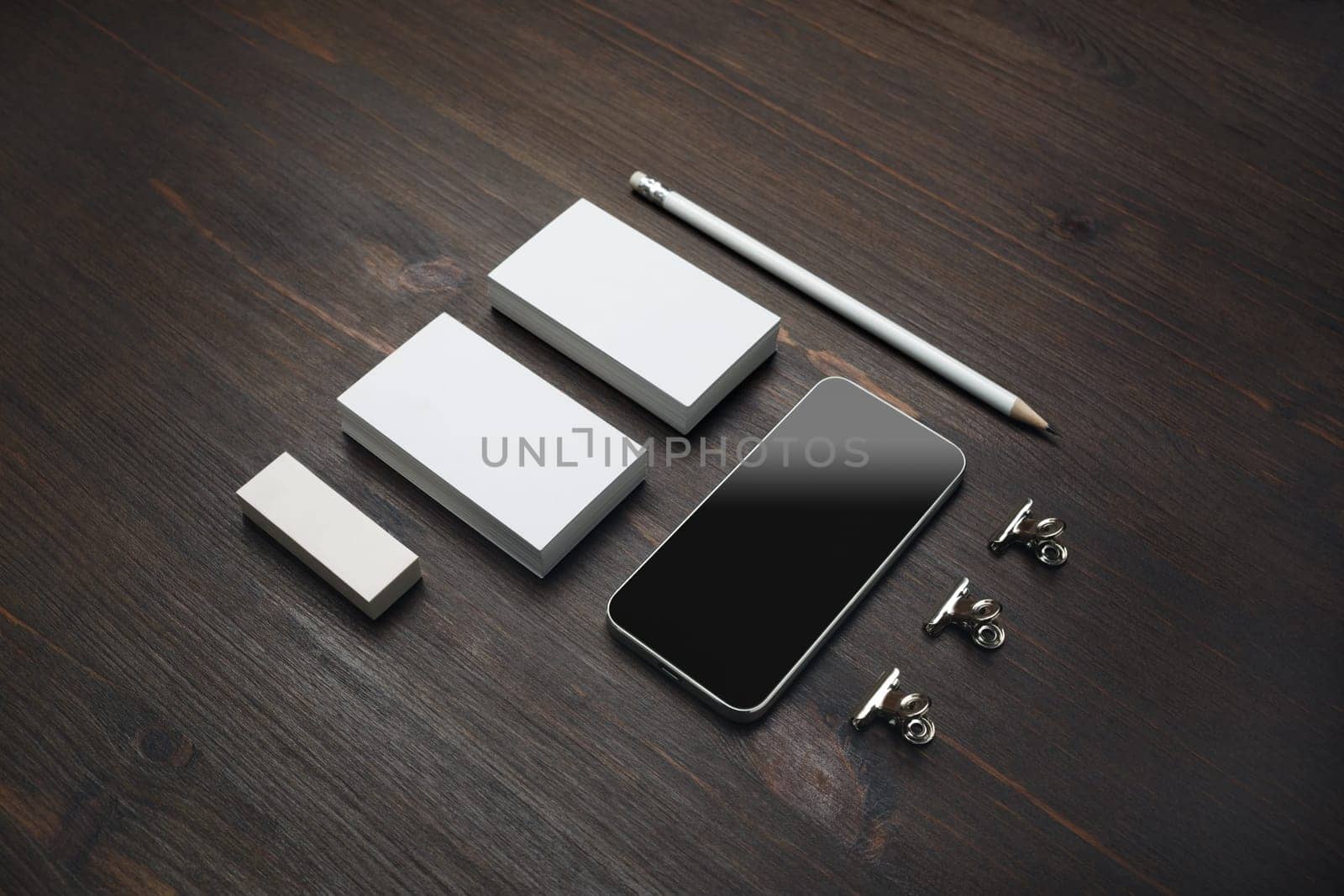 Smartphone and blank stationery: business cards, pencil and eraser on wooden background.
