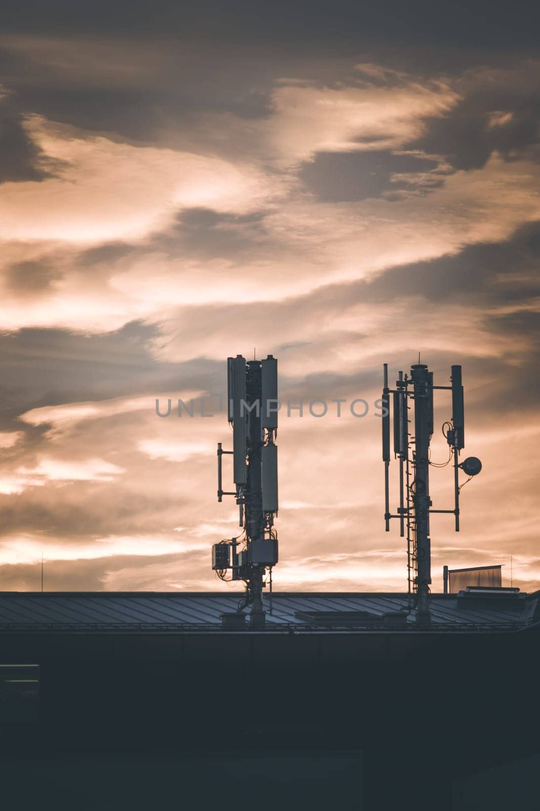 Transmitter antennas in the evening. Orange sky and clouds.