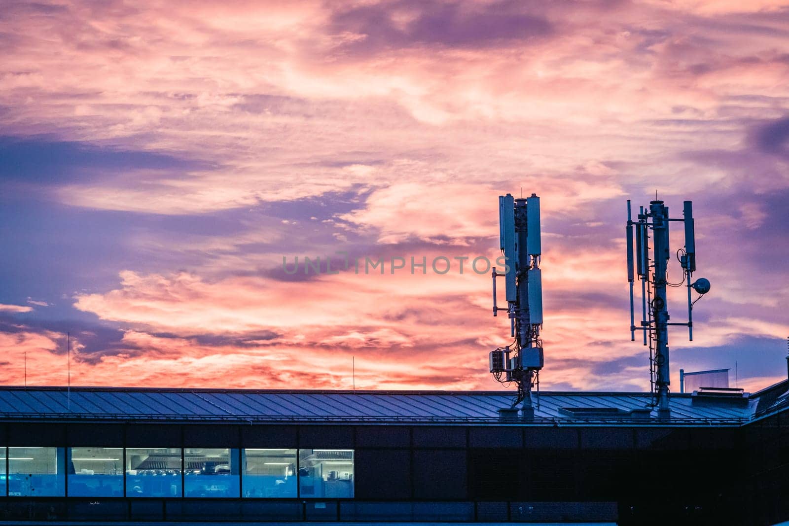 Transmitter antennas in the evening. Orange sky and clouds.