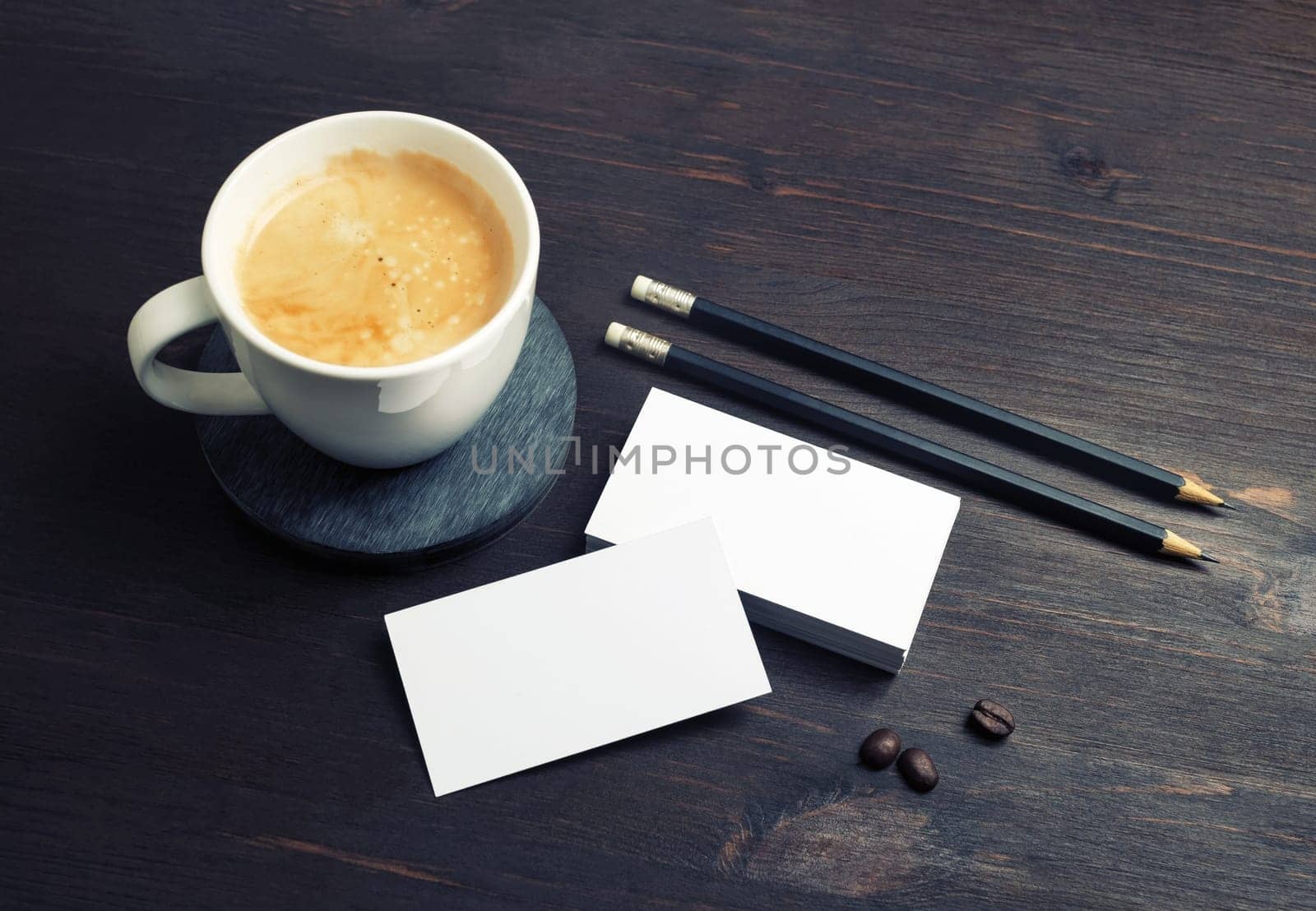 Coffee cup, blank white business cards and pencils on wood table background. Responsive design template.