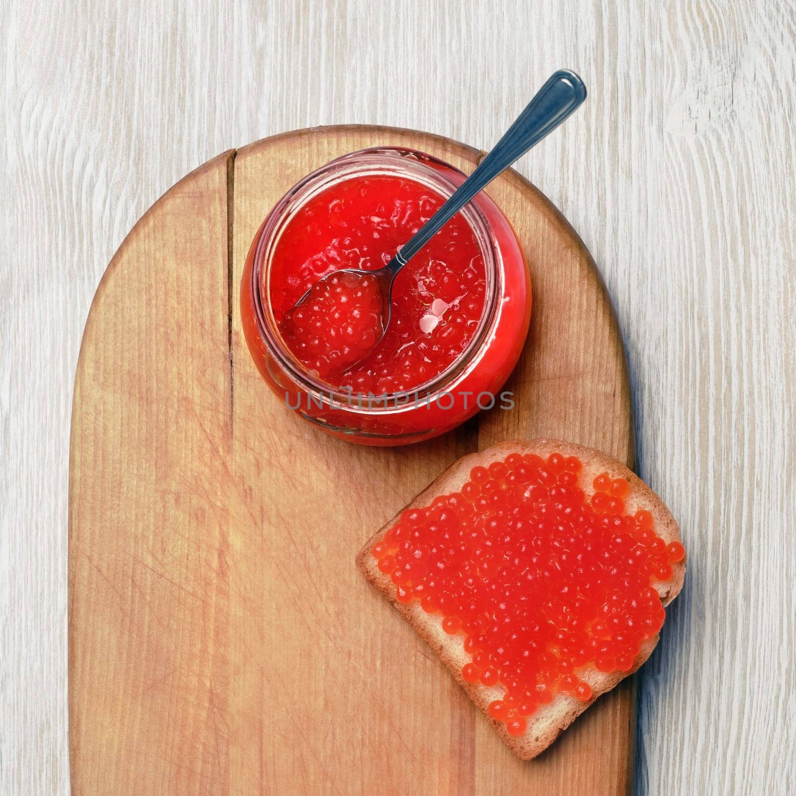 Fresh delicious caviar. Sandwich with red caviar, glass jar and spoon. Flat lay.