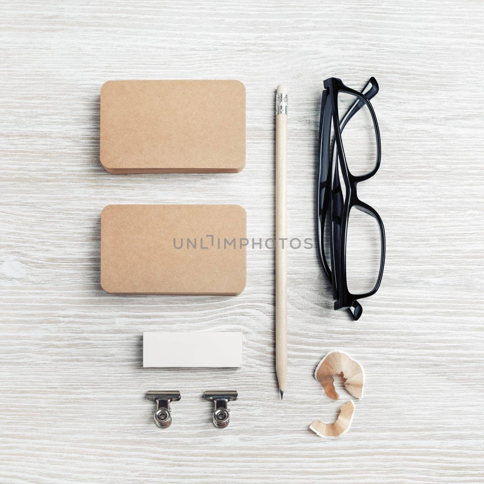 Kraft business cards, glasses, pencil and eraser on light wooden background. Top view. Flat lay.
