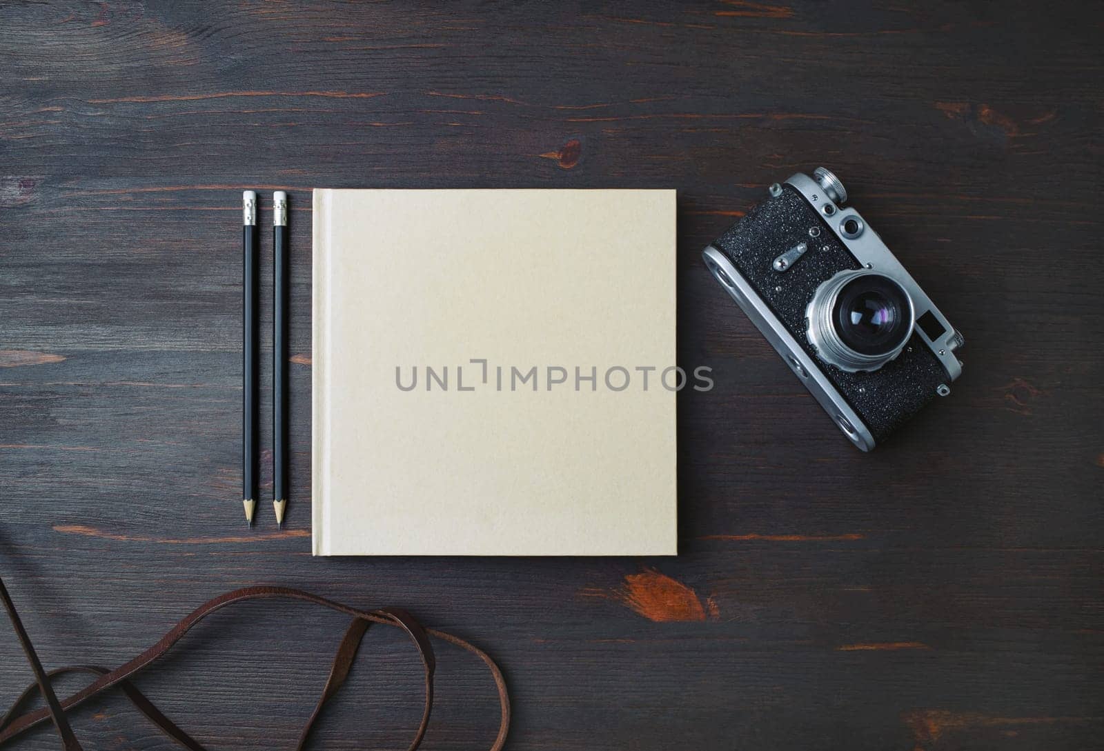 Blank stationery: book, pencils and retro camera on wood table background. Flat lay.