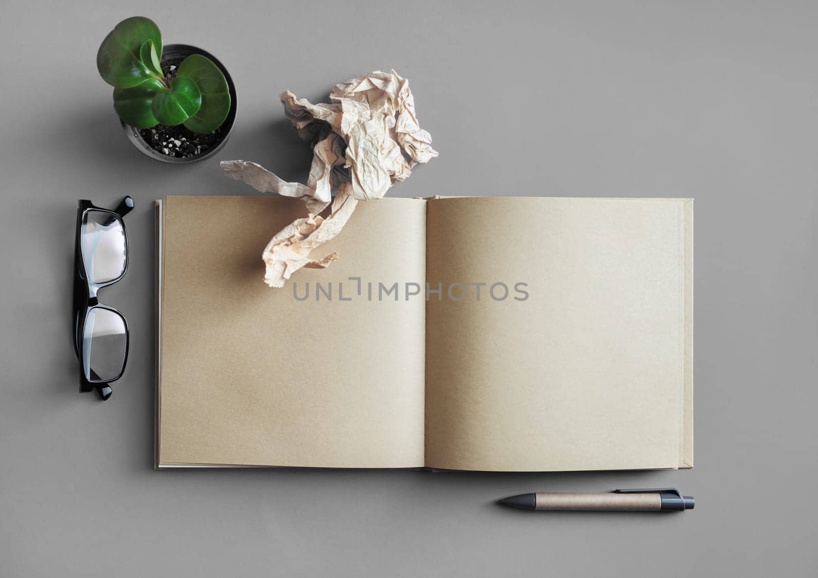 Blank kraft book, stationery and plant on gray paper background. Responsive design mockup. Top view. Flat lay.