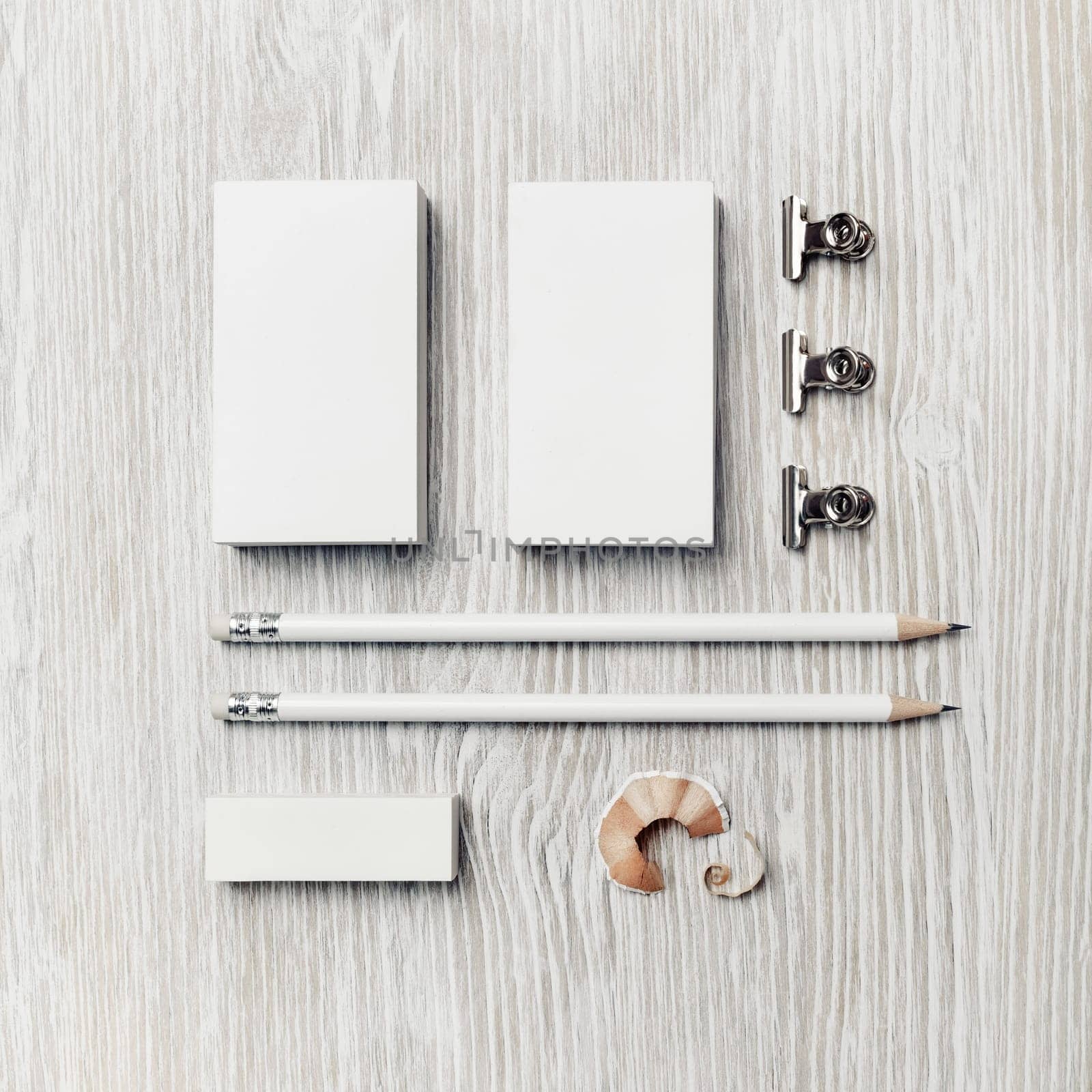 Photo of blank stationery template on light wooden background. Business cards, pencils and eraser. Top view. Flat lay.