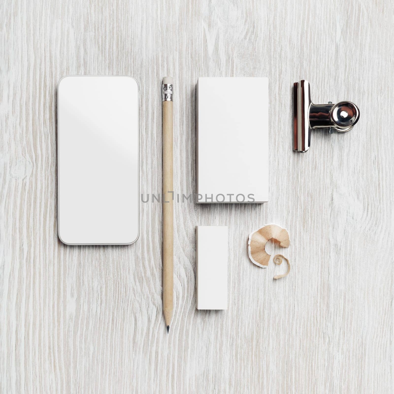 Smartphone, blank business card, pencil and eraser on light wood table background. Branding mock up. Top view. Flat lay.