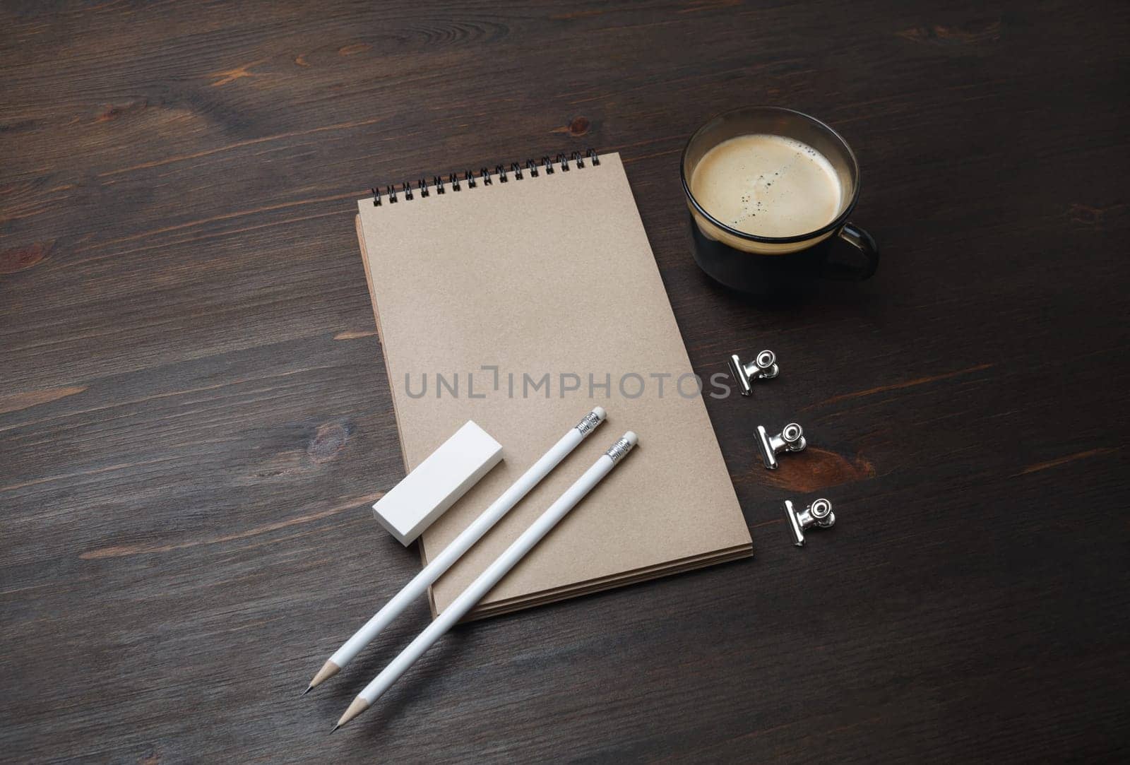Blank stationery template. Blank kraft notebook, coffee cup, pencil and eraser on wood table background.