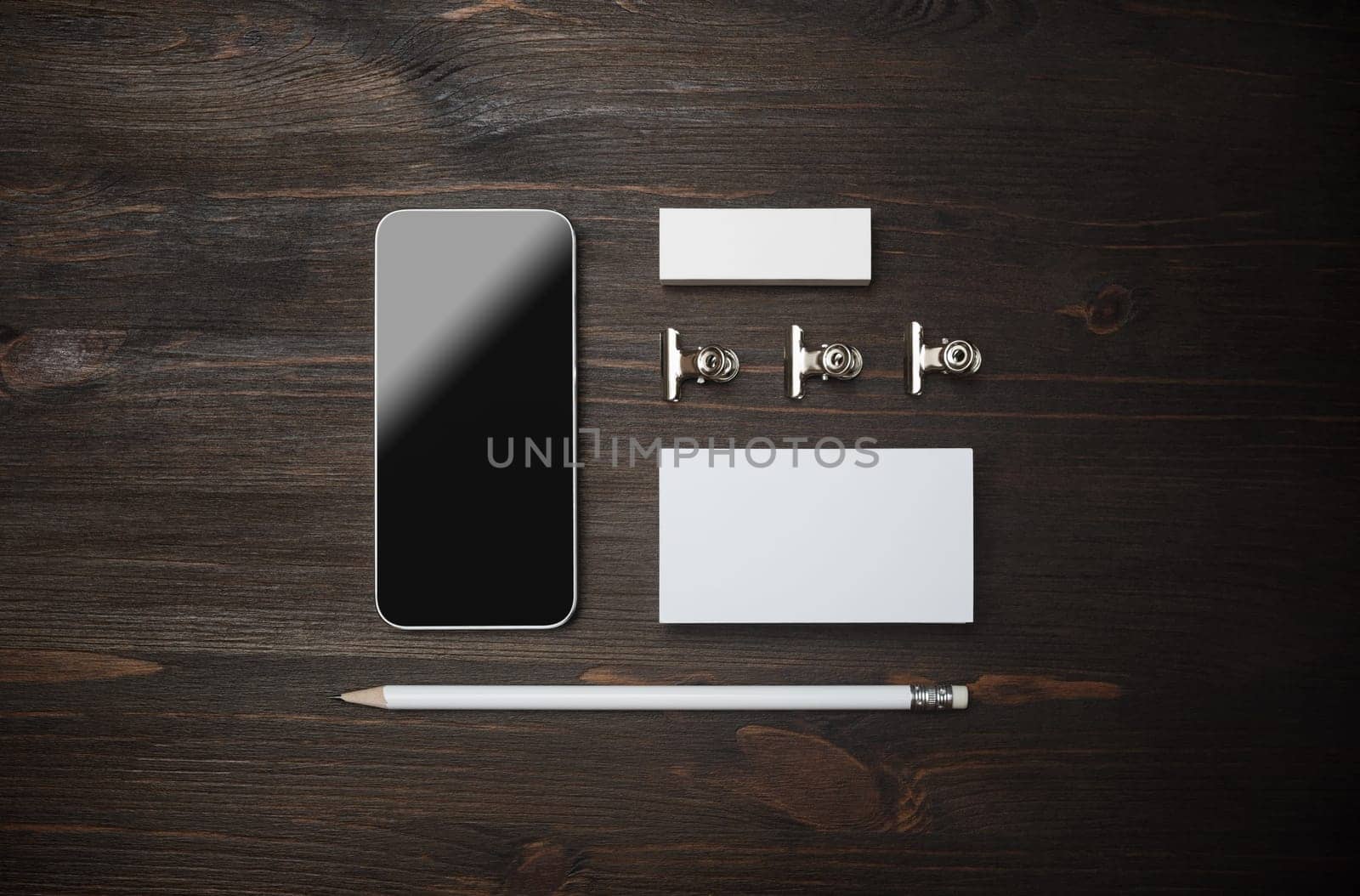 Corporate identity template. Smartphone, blank business card, pencil and eraser on wooden background. Flat lay.