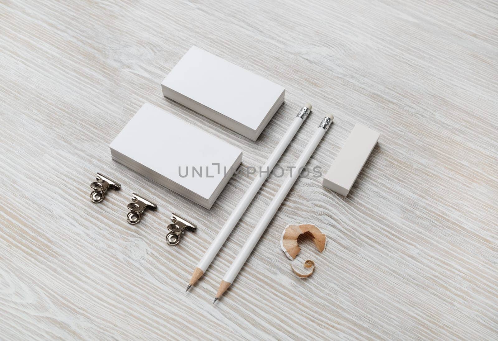 Blank white business cards, pencil and eraser on light wooden background. Template for branding design.