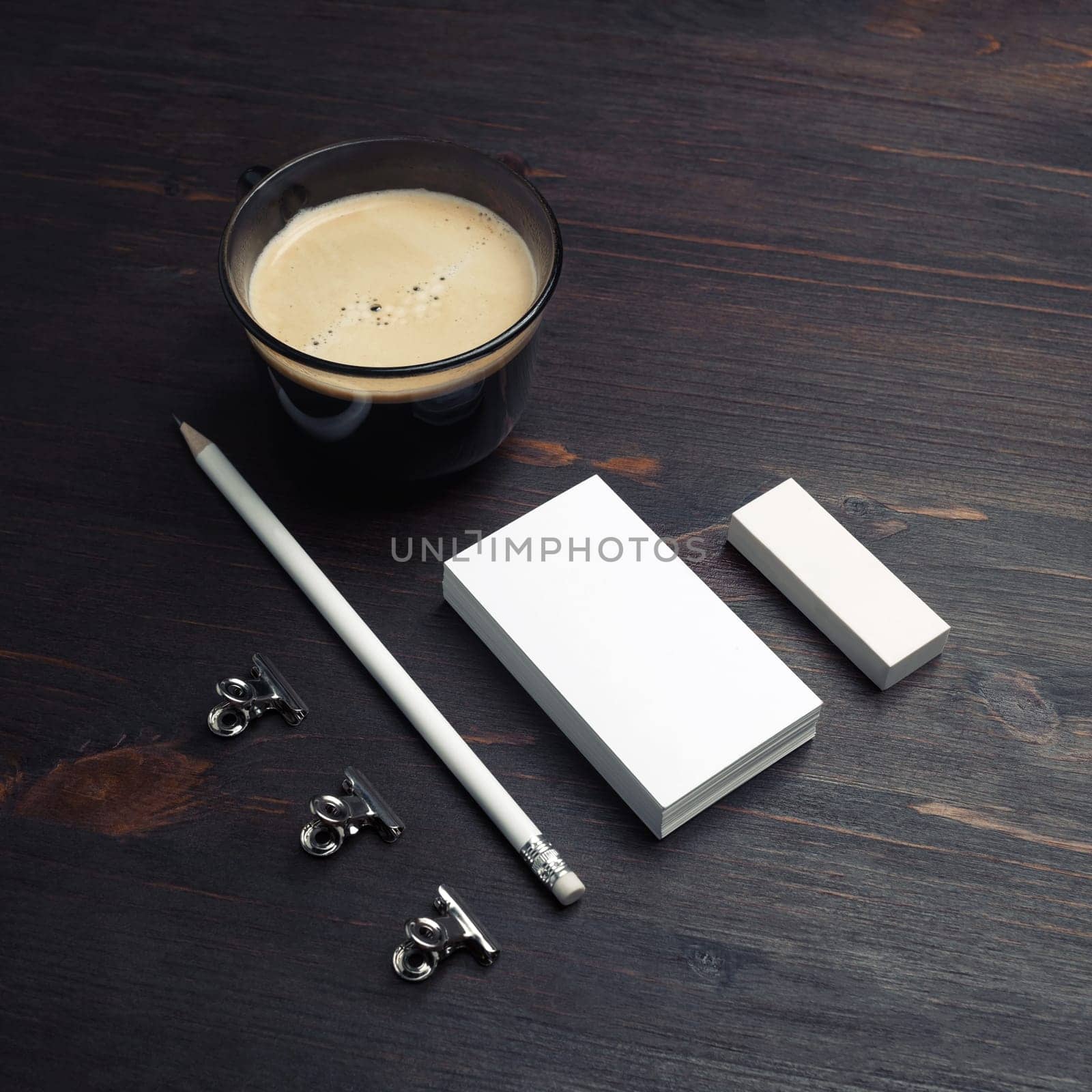 Coffee cup, blank business cards, pencil and eraser on wood table background.