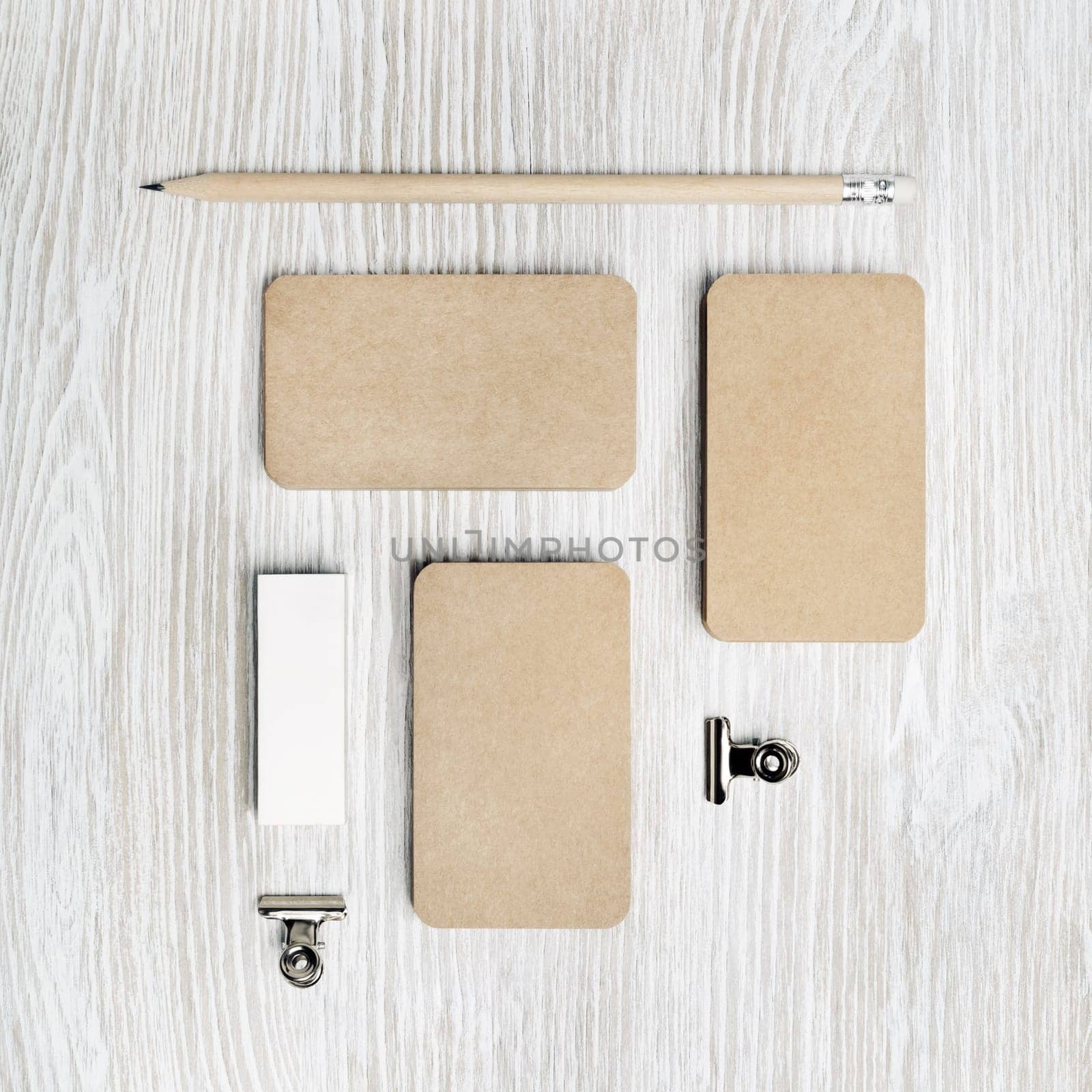 Blank kraft business cards, pencil and eraser on light wood table background. Blank stationery set. Top view. Flat lay.