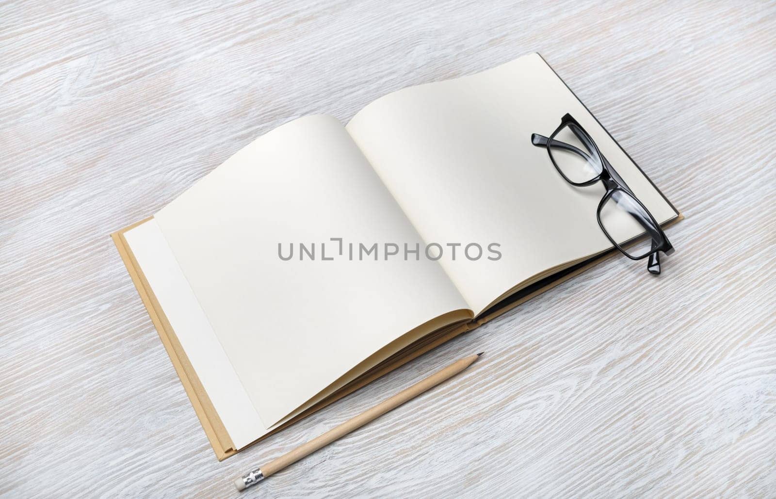 Photo of open book with blank pages, glasses and pencil on light wood table background. Responsive design template.