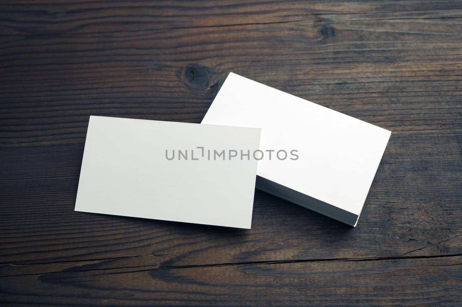 Blank white business cards on wooden background. Mockup for branding identity. Template for graphic designers portfolios.