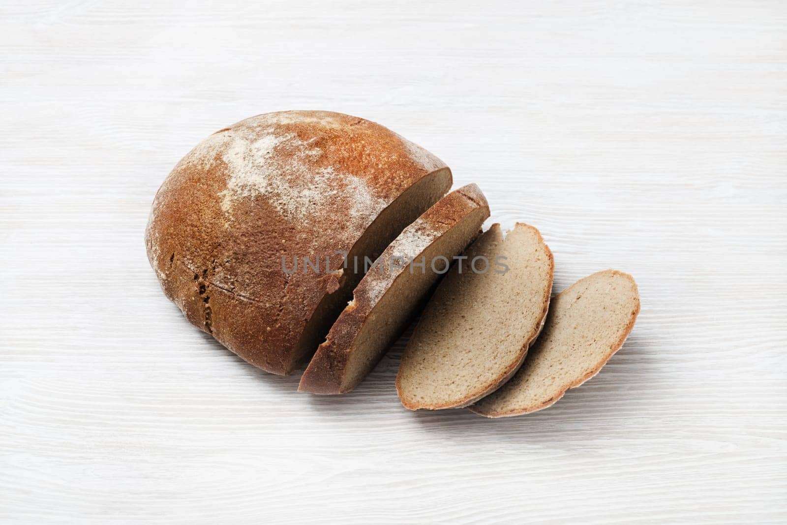 Sliced fresh bread on light wooden background.