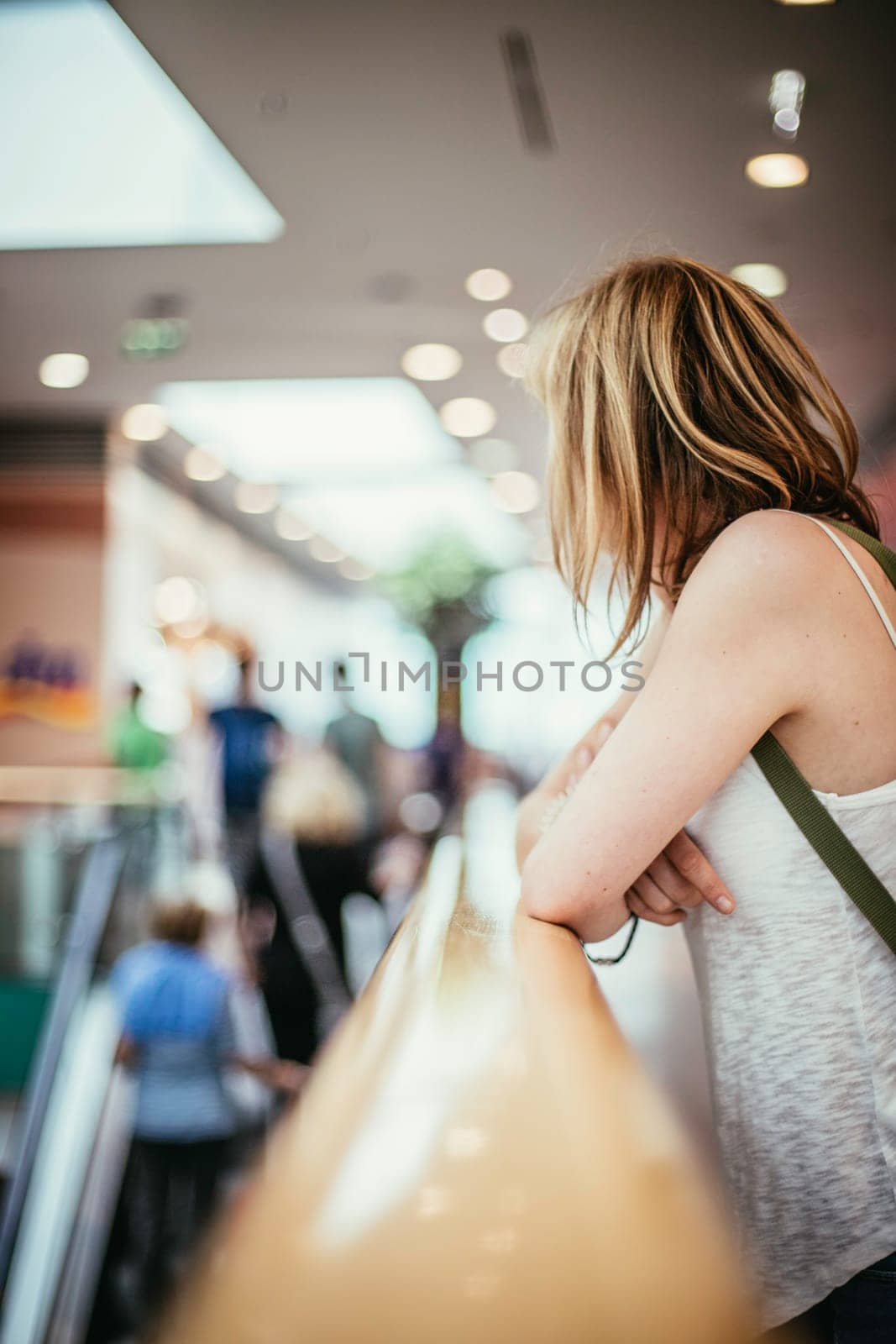 Young girl is leaning on the handrail in a shopping mall, blurry background
