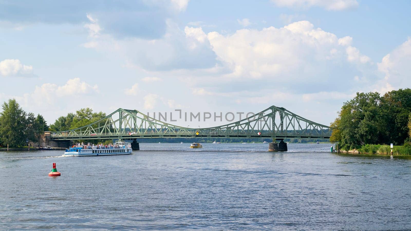 The Glienicke Bridge over the Havel River between Potsdam and Berlin. In the foreground an excursion boat with tourists.