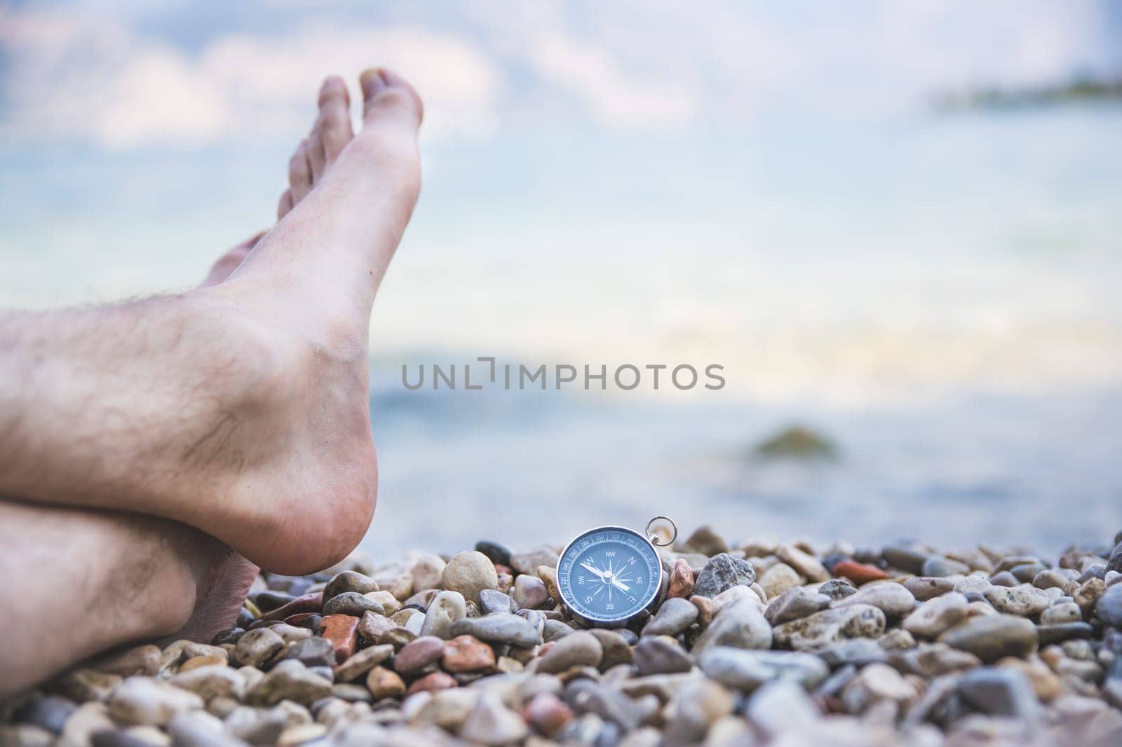 Compass and mans feet on beach, enjoy and text space