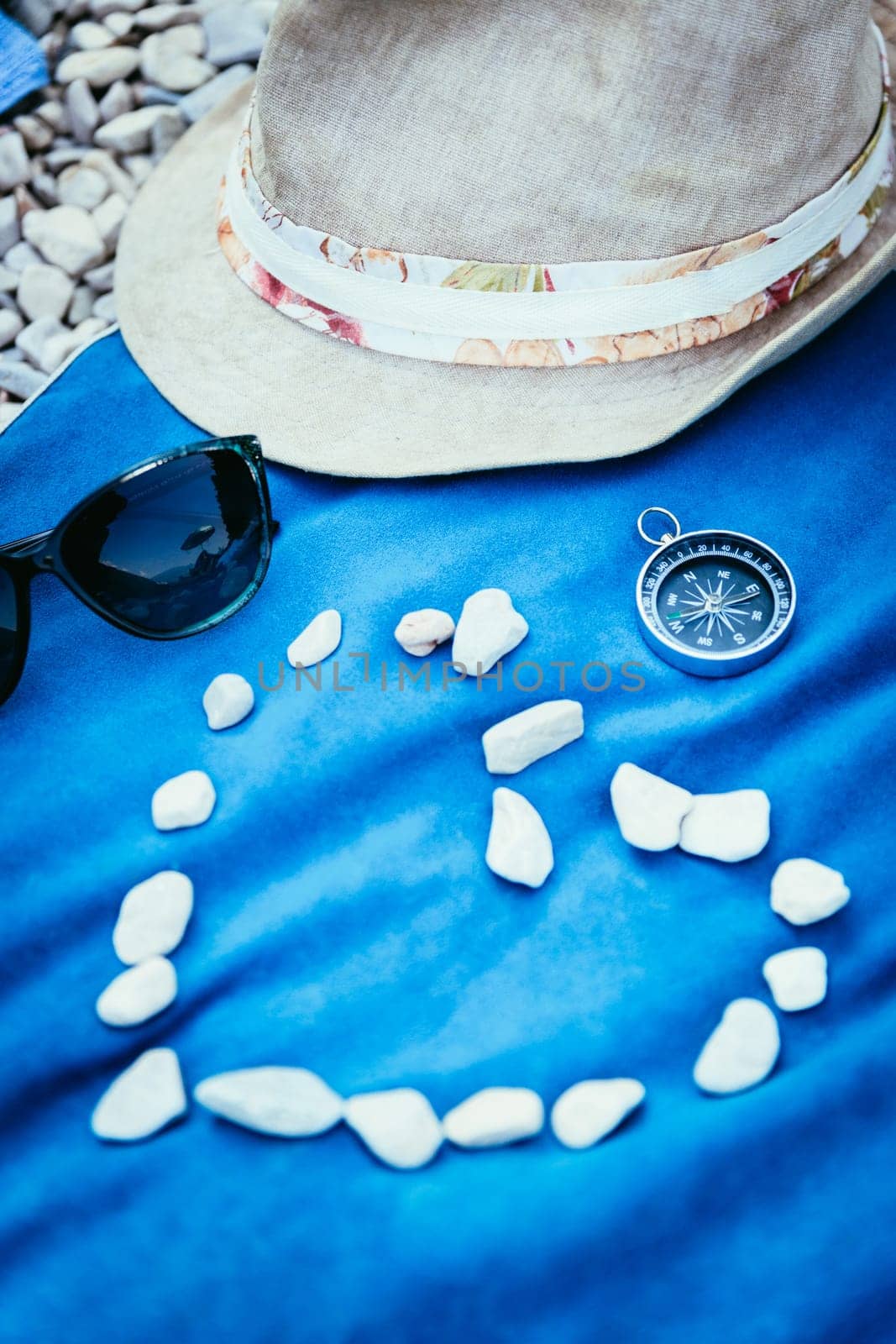 Summer holiday vacation accessories on beach, heart out of stones
