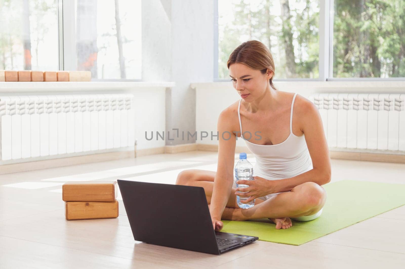 Young fit woman in sportswear watching online video with fitness exercises on laptop and doing push ups at home. Pretty lady burning calories, practice pilates. Distant training with personal trainer