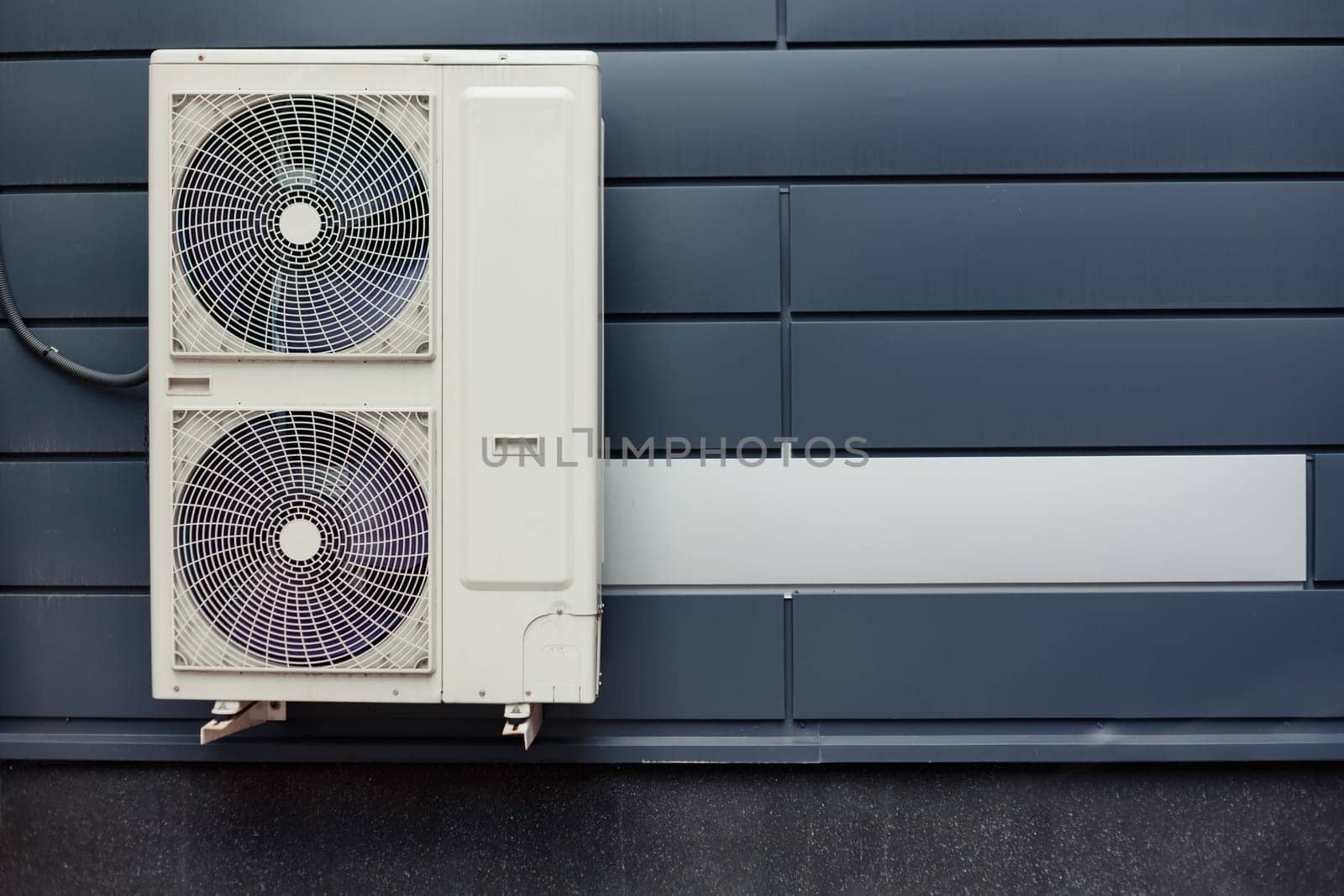 Air compressor installation on metal tiled wall of modern building.