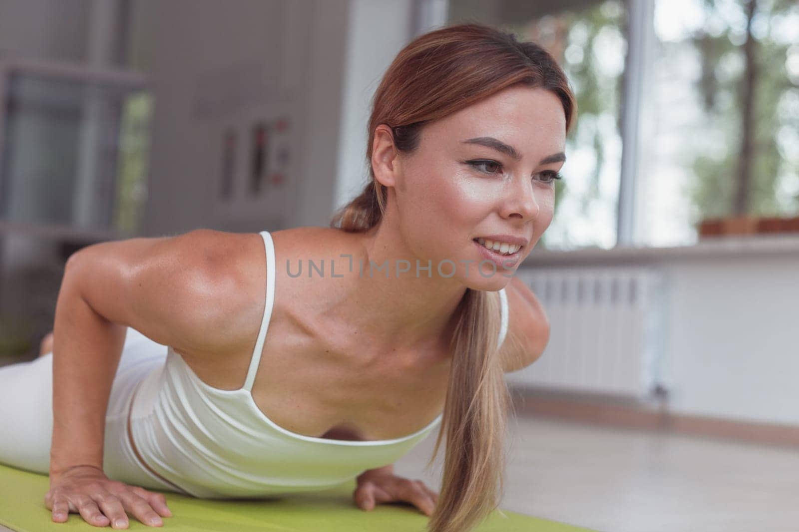 Young woman on a yoga mat doing the dolphin plank pose