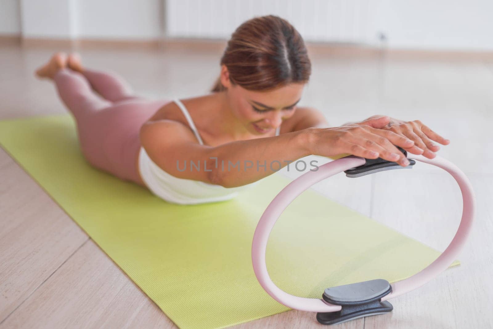Exercises with pilates ring. Woman doing aerobics workout at sport gym with panoramic windows.