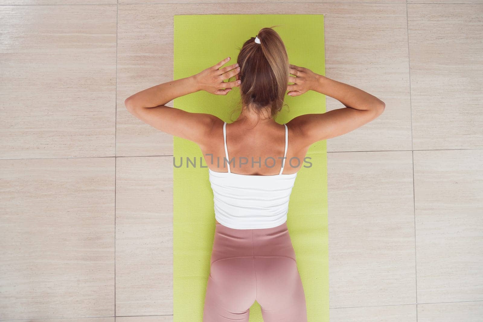 Woman doing back extension exercise on fit ball with online trainer. Top view