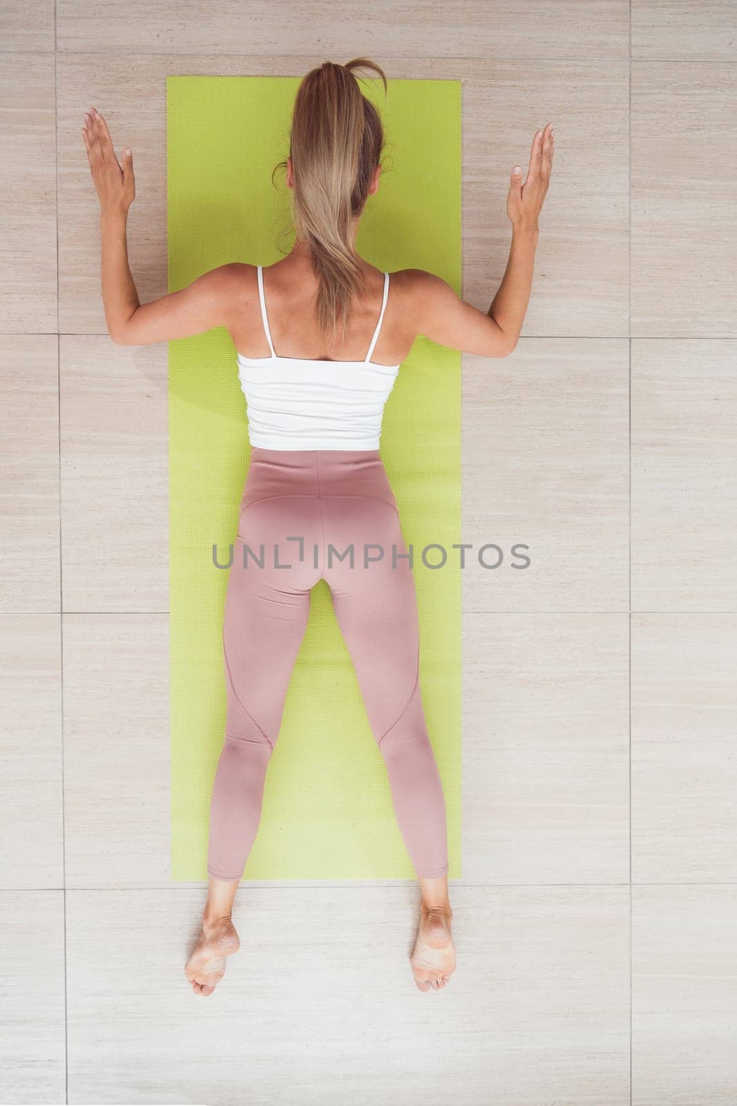 Woman doing back extension exercise on fit ball with online trainer. Top view