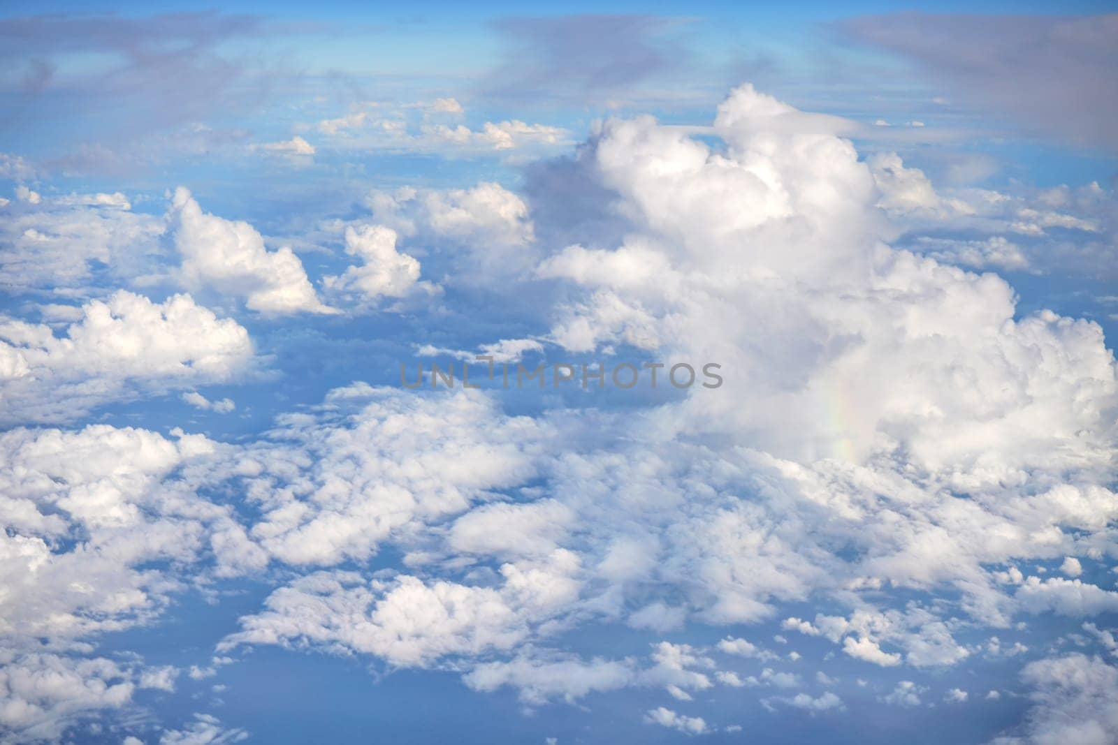 Fluffy sky clouds lit by afternoon sun, as seen from commercial airplane flying over.