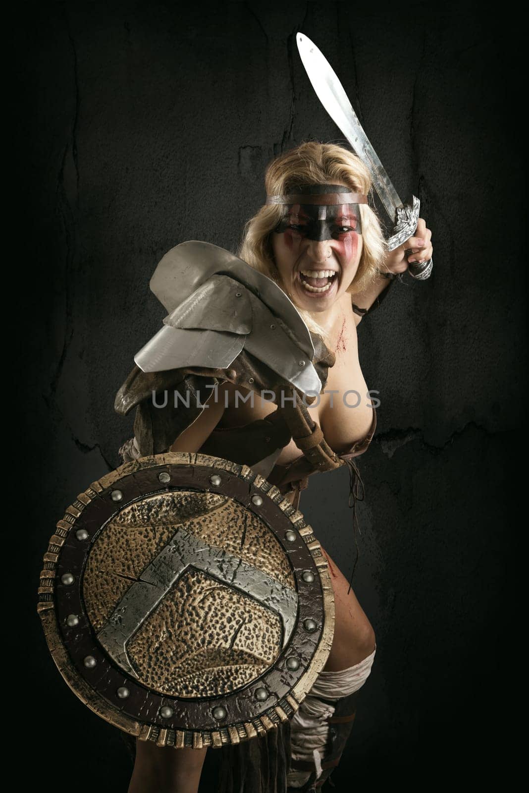 Ancient woman warrior or Gladiator posing with sword and shield, isolated in a dark background