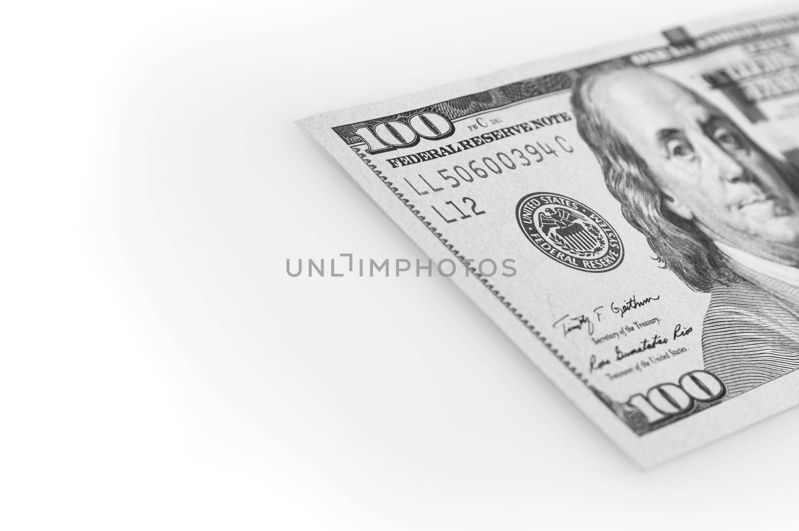 A hundred-dollar bill on a white background. The one hundred North American dollars bill is not fully positioned diagonally. Selective focus on a portion of the 100 bill. Black and white style. Place for logo, lettering, layout, layout.