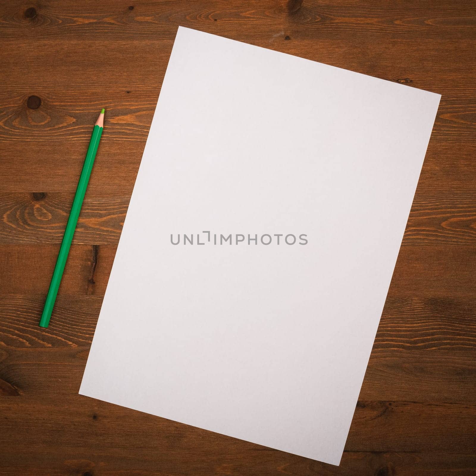 A blank white sheet and pencil for drawing on a wooden background with space for copying and lettering. Layout, mockup free space.