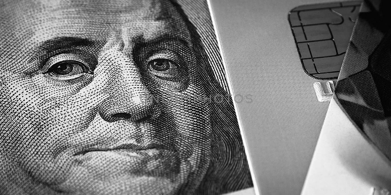 Benjamin Franklin's face on a hundred-dollar bill next to a credit card. Close-up. A hundred-dollar American bill with the eyes of Benjamin Franklin. Black and white style. Layout, template, layout.